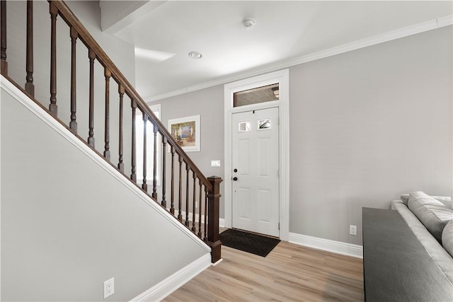 foyer entrance featuring stairs, light wood-type flooring, crown molding, and baseboards