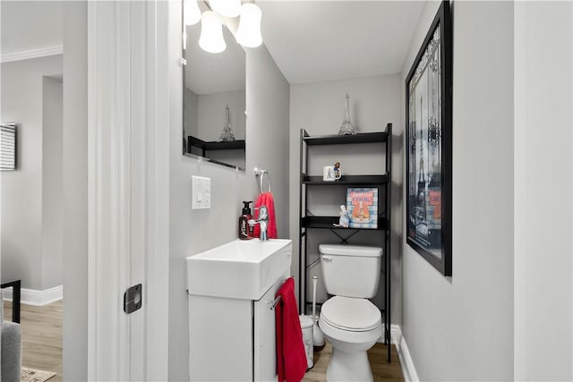 bathroom featuring baseboards, toilet, wood finished floors, and vanity