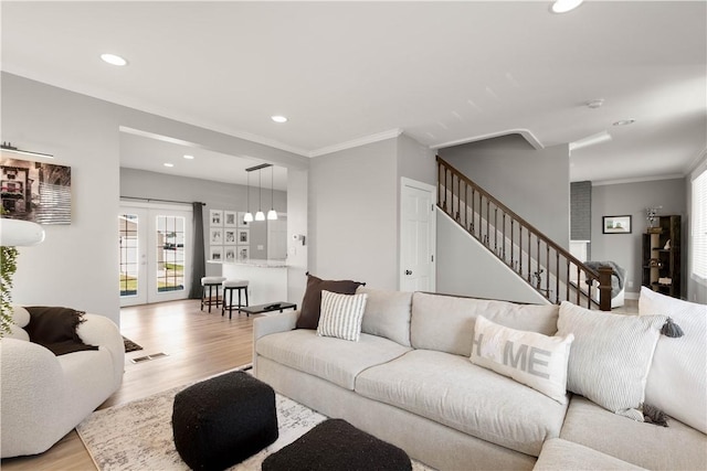 living area with stairway, french doors, crown molding, and light wood-style floors