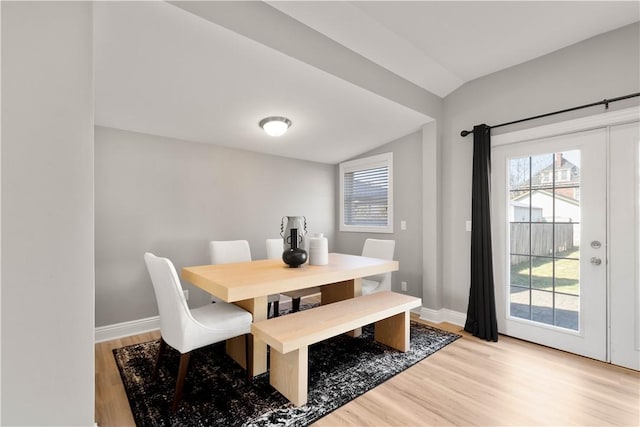 dining space with light wood finished floors, french doors, baseboards, and lofted ceiling