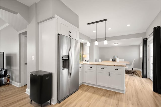 kitchen with stainless steel fridge, a peninsula, and light wood finished floors