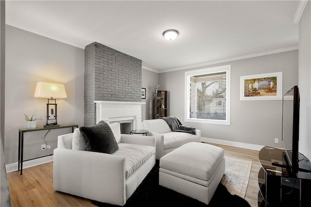 living room with baseboards, a fireplace, light wood-style flooring, and crown molding