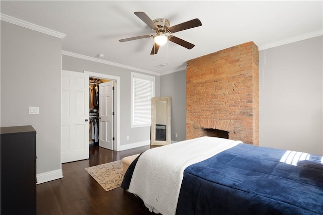 bedroom featuring a walk in closet, crown molding, baseboards, and wood finished floors