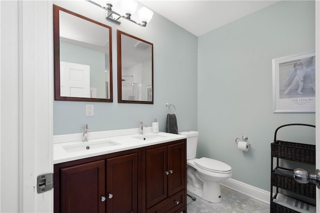 bathroom with a sink, baseboards, toilet, and double vanity