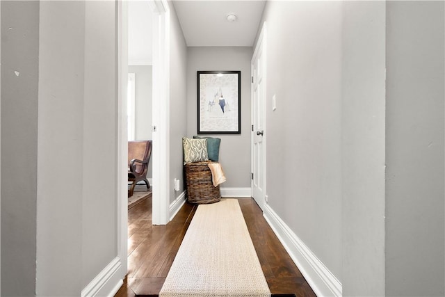 hall featuring baseboards and dark wood-type flooring