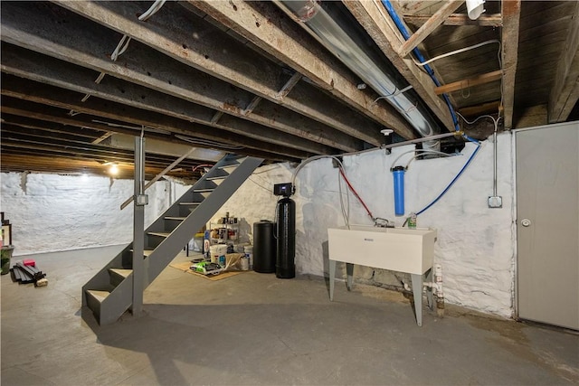 unfinished basement featuring stairway and a sink