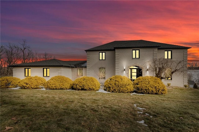 view of front of property with a lawn and brick siding