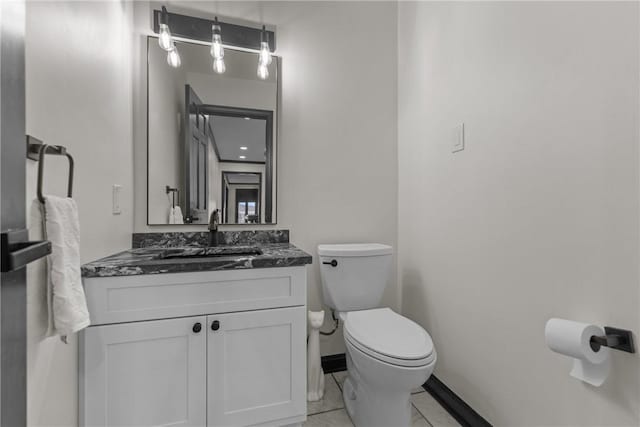 half bath featuring toilet, vanity, and baseboards