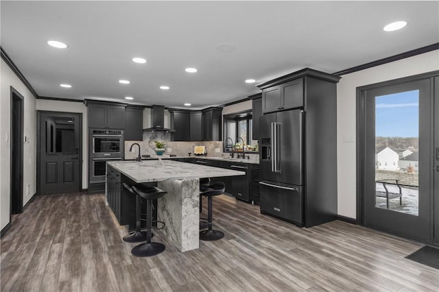 kitchen with a kitchen bar, crown molding, wall chimney range hood, high quality fridge, and backsplash