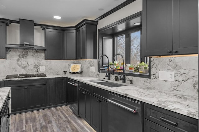 kitchen with a sink, wood finished floors, wall chimney range hood, light stone countertops, and stainless steel gas cooktop