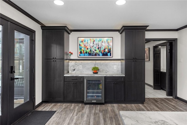 bar with beverage cooler, backsplash, a bar, and crown molding