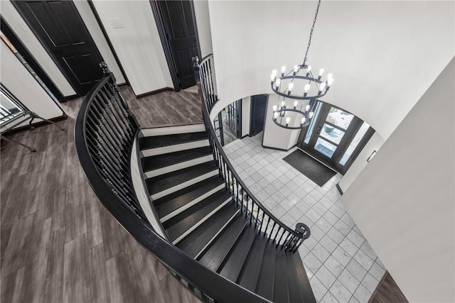 stairway featuring arched walkways, a chandelier, a high ceiling, and wood finished floors