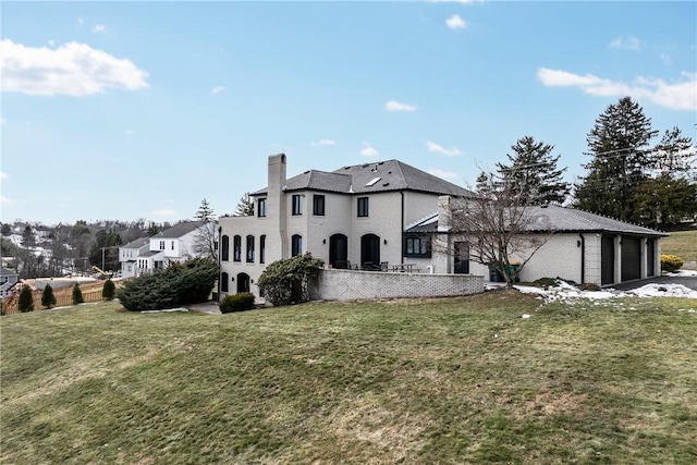 rear view of house with a lawn, an attached garage, and a chimney