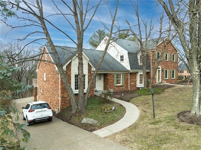 view of front of property featuring brick siding, a shingled roof, and a front lawn