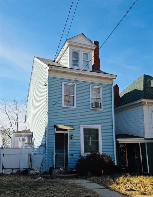 view of front of home featuring a chimney and fence