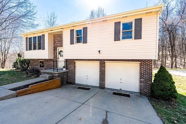 split foyer home with concrete driveway, a garage, and brick siding