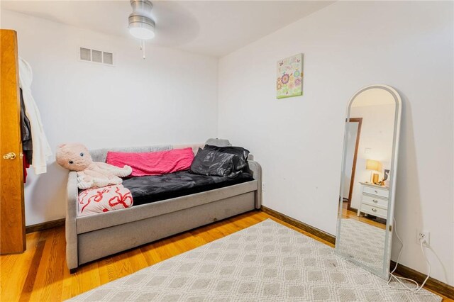 bedroom with wood finished floors, baseboards, visible vents, arched walkways, and ceiling fan