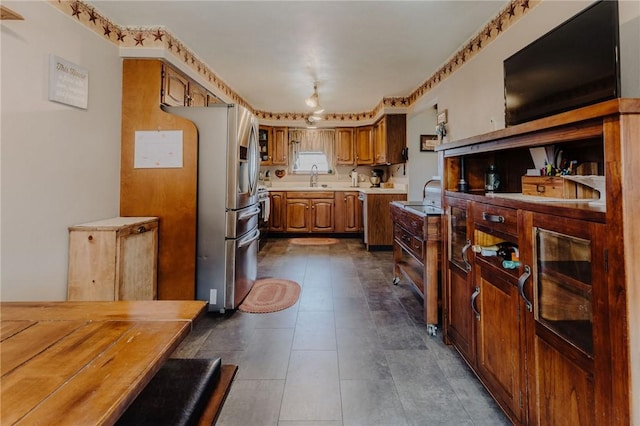 kitchen featuring a sink, brown cabinets, stainless steel fridge with ice dispenser, and light countertops