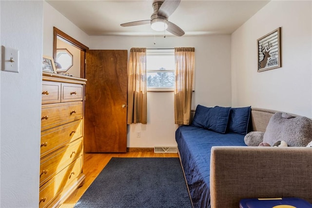 bedroom with ceiling fan, visible vents, and wood finished floors