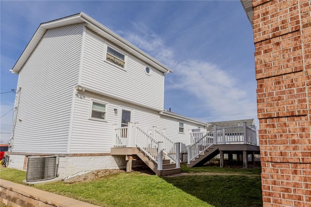 rear view of property featuring a lawn, central AC, and a wooden deck