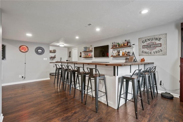 bar with dark wood-style floors, visible vents, baseboards, wet bar, and recessed lighting