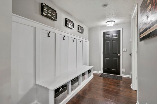 mudroom featuring baseboards, a textured ceiling, and dark wood-style flooring