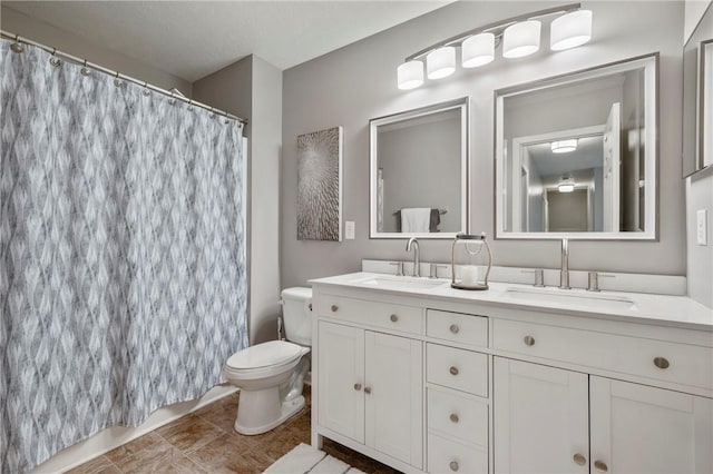 bathroom featuring a shower with shower curtain, double vanity, toilet, and a sink