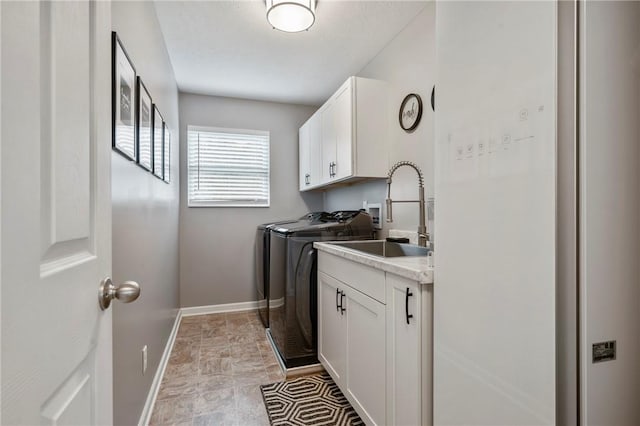 laundry room featuring a sink, baseboards, cabinet space, and separate washer and dryer