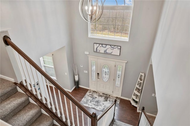 foyer entrance featuring dark wood-type flooring, a healthy amount of sunlight, baseboards, and a towering ceiling