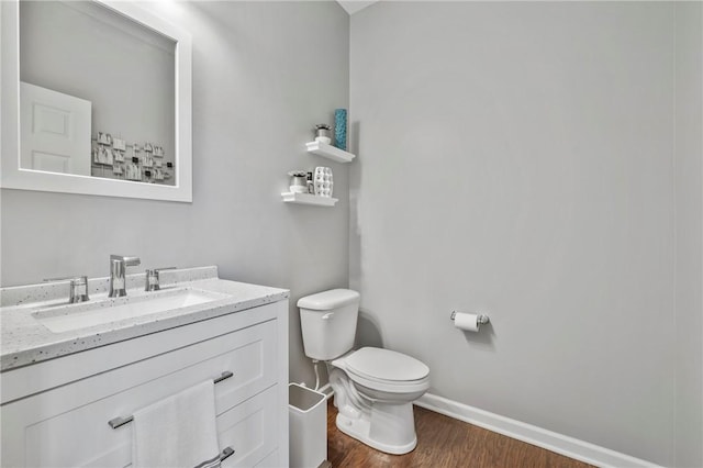 bathroom featuring vanity, toilet, wood finished floors, and baseboards