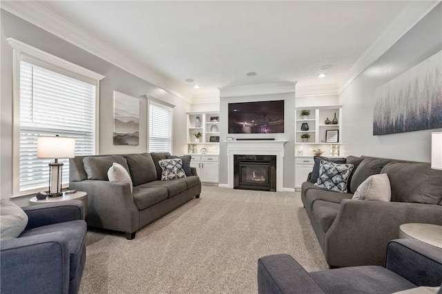 living room with built in features, light colored carpet, a glass covered fireplace, and crown molding