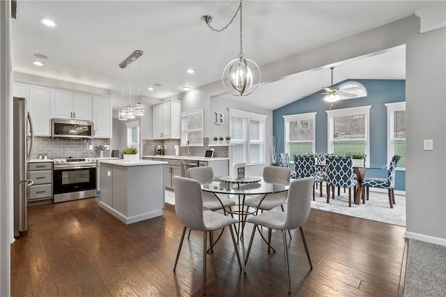 dining area featuring dark wood-type flooring, lofted ceiling, ceiling fan with notable chandelier, recessed lighting, and baseboards