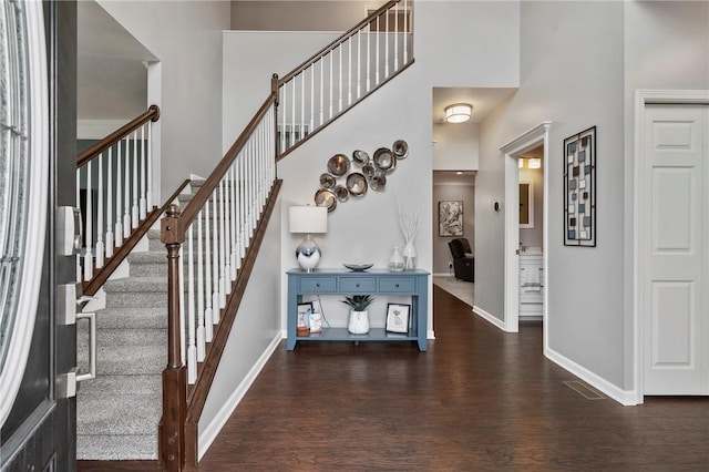 stairway featuring a high ceiling, wood finished floors, and baseboards