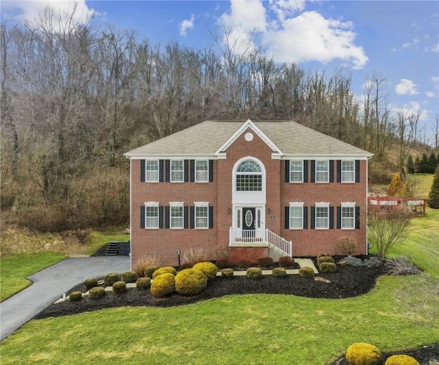 view of front of property featuring brick siding, driveway, and a front yard