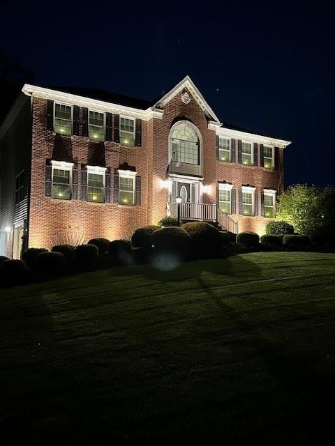 colonial-style house with a lawn and brick siding