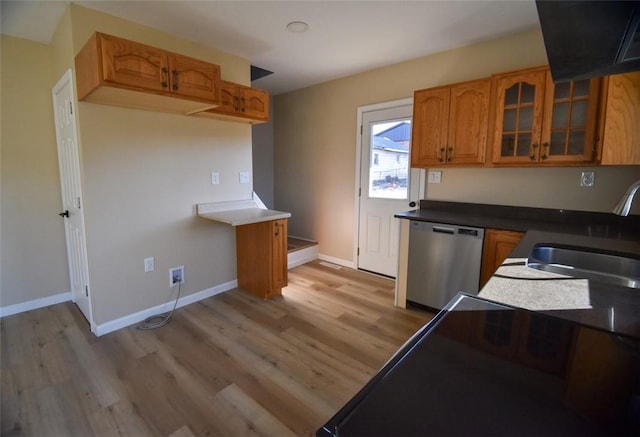 kitchen with brown cabinetry, a sink, glass insert cabinets, light wood-style floors, and dishwasher