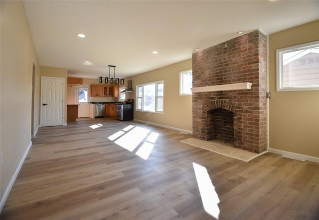 unfurnished living room with recessed lighting, a fireplace, light wood-style floors, and baseboards