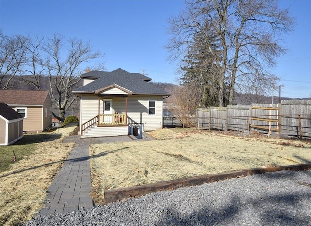 bungalow-style home featuring an outbuilding, roof with shingles, and fence