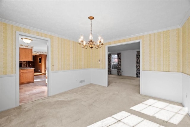 spare room with visible vents, a wainscoted wall, wallpapered walls, ornamental molding, and light carpet