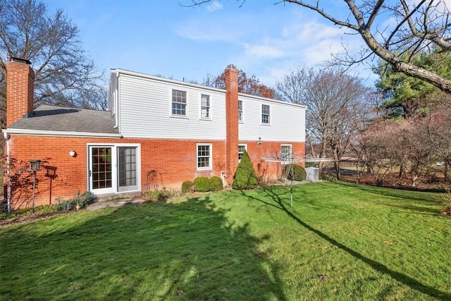 back of property with brick siding, a lawn, and a chimney