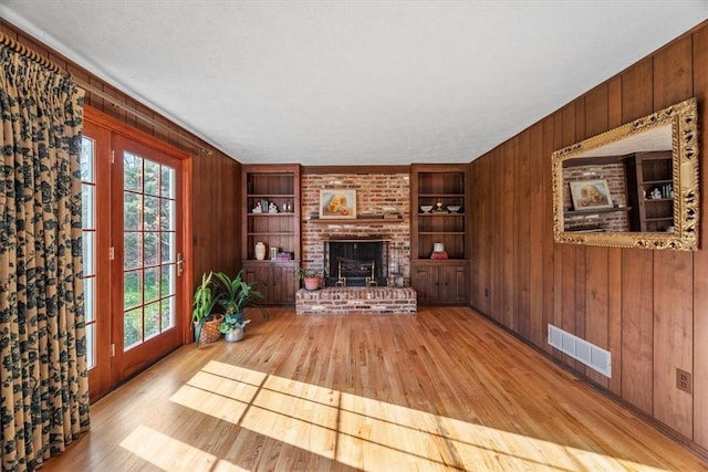 living area featuring a wealth of natural light, visible vents, wood walls, and built in shelves