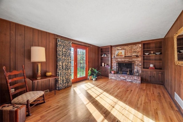 living area with wooden walls, built in features, a fireplace, and wood finished floors