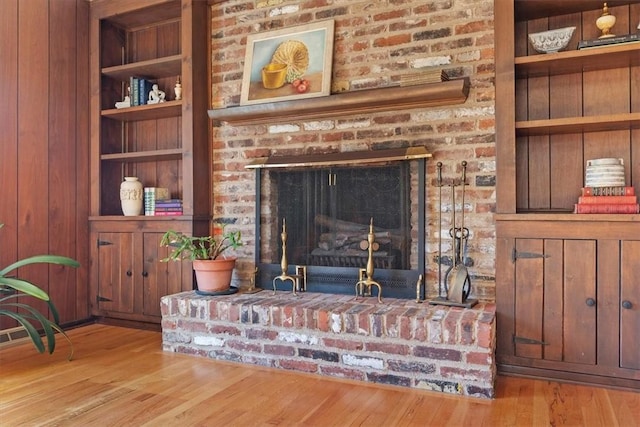 living room featuring built in features, a fireplace, and wood finished floors