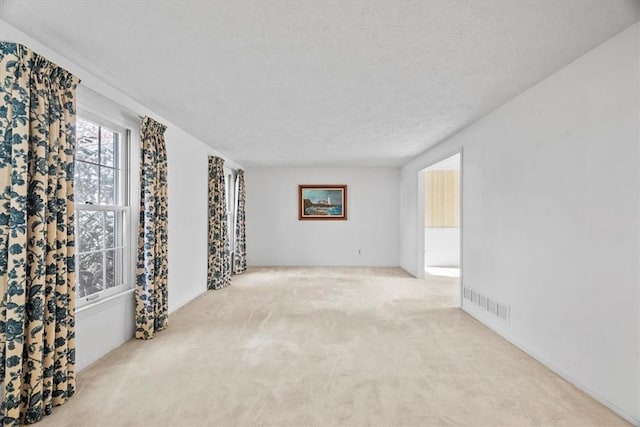 carpeted spare room featuring visible vents and a textured ceiling