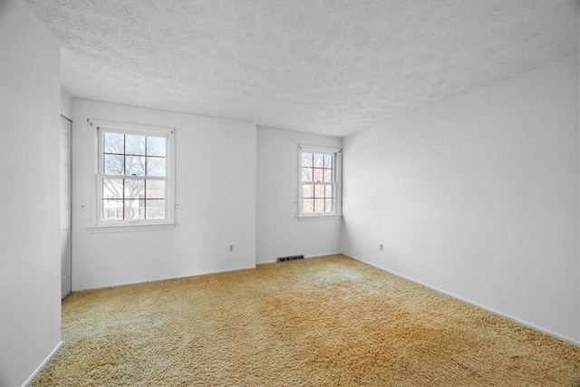 empty room featuring visible vents, carpet floors, and a textured ceiling