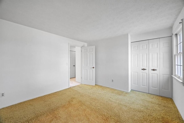 unfurnished bedroom featuring a closet, a textured ceiling, and carpet flooring