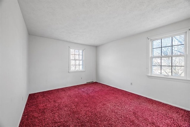 carpeted empty room with visible vents and a textured ceiling