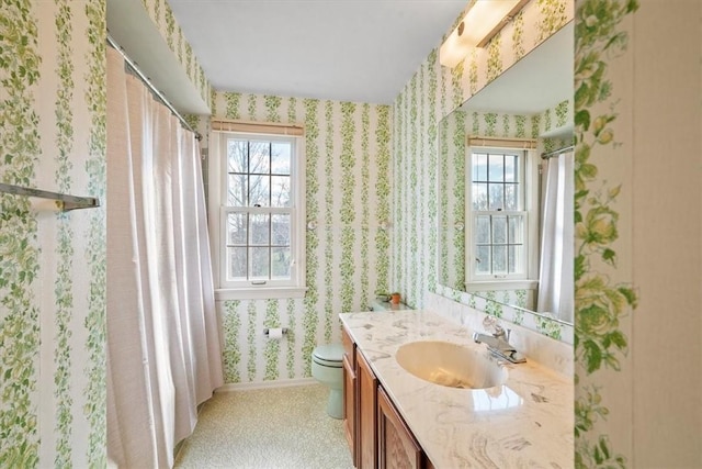 full bathroom featuring plenty of natural light, toilet, wallpapered walls, and vanity