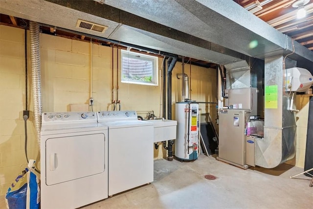 below grade area with visible vents, washer and dryer, a sink, heating unit, and water heater