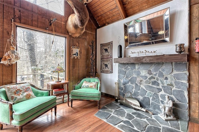 sitting room with lofted ceiling with beams, wood ceiling, wooden walls, and wood finished floors